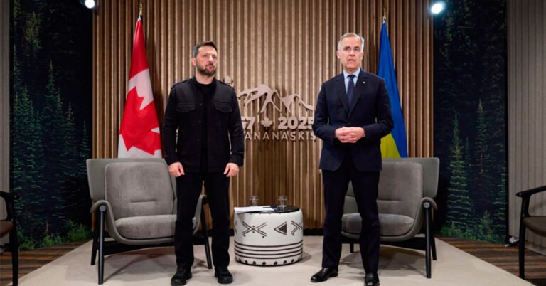 Володимир Зеленський у чорному одязі та Марк Карні у темно-синьому костюмі стоять поруч на фоні прапорів Канади та України та емблеми G7. Між ними стоїть маленький столик з напоями.