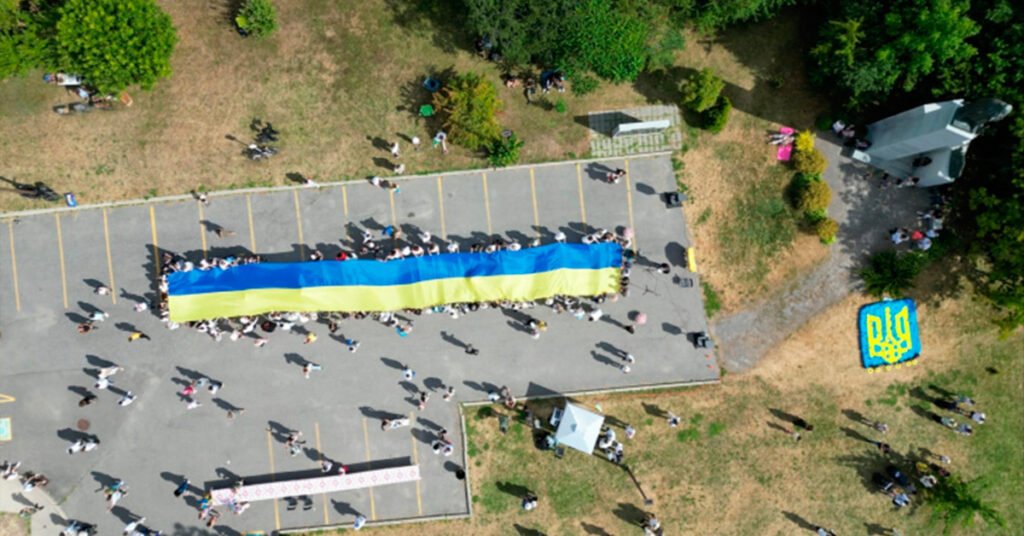 Група українців в Оттаві тримає 30-метровий синьо-жовтий прапор під час святкування Дня Незалежності України.