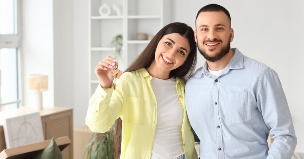 Щаслива молода пара тримає ключі від нової квартири в Канаді на фоні світлої кімнати