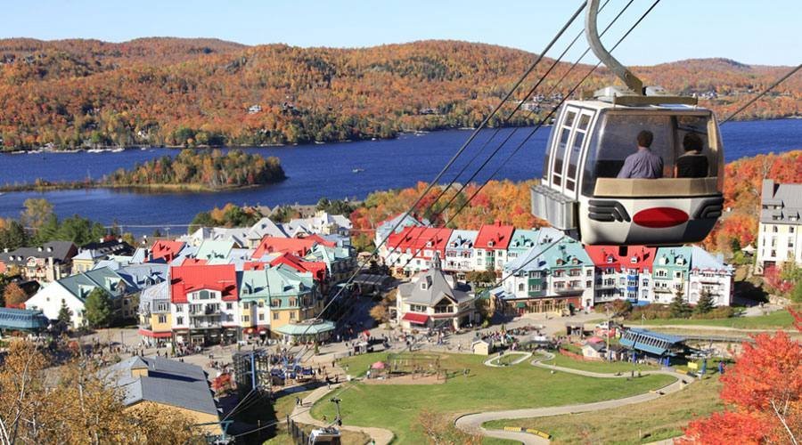 Кабінка канатної дороги над мальовничим містечком Мон-Трамблан у Квебеку на фоні осіннього лісу та озера