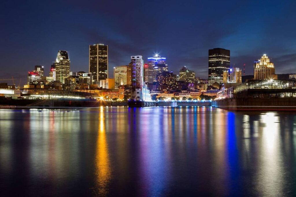 Нічний вид на хмарочоси Монреаля з яскравими вогнями, що відображаються у воді