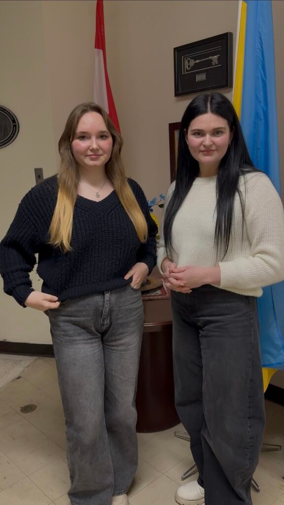 Софія Рочева та Каріна Торговецька на фоні прапорів України та Канади