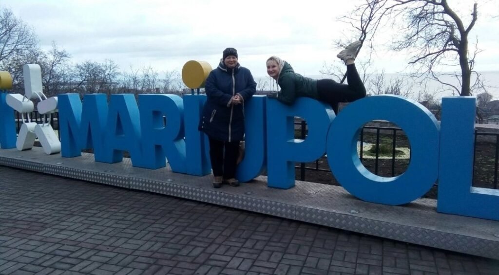 Альона Пархоменко з мамою біля великого синього напису Маріуполь у Міському саду