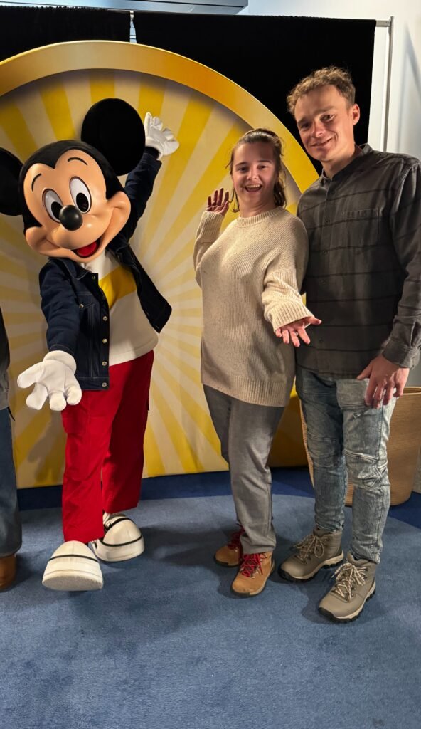 Таня Дубчак та Назар Макаренко позують поруч із Міккі Маусом на яскравому жовтому фоні