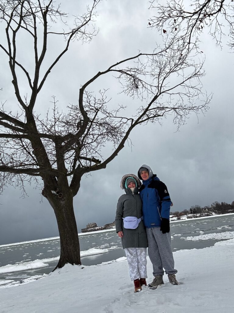 Таня і Назар на засніженому узбережжі озера Онтаріо біля великого дерева взимку