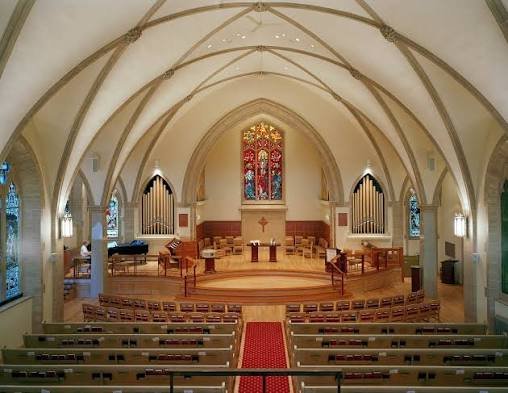 Внутрішній вигляд церкви Rosedale United Church з високими білими склепіннями, вітражем по центру та органними трубами.