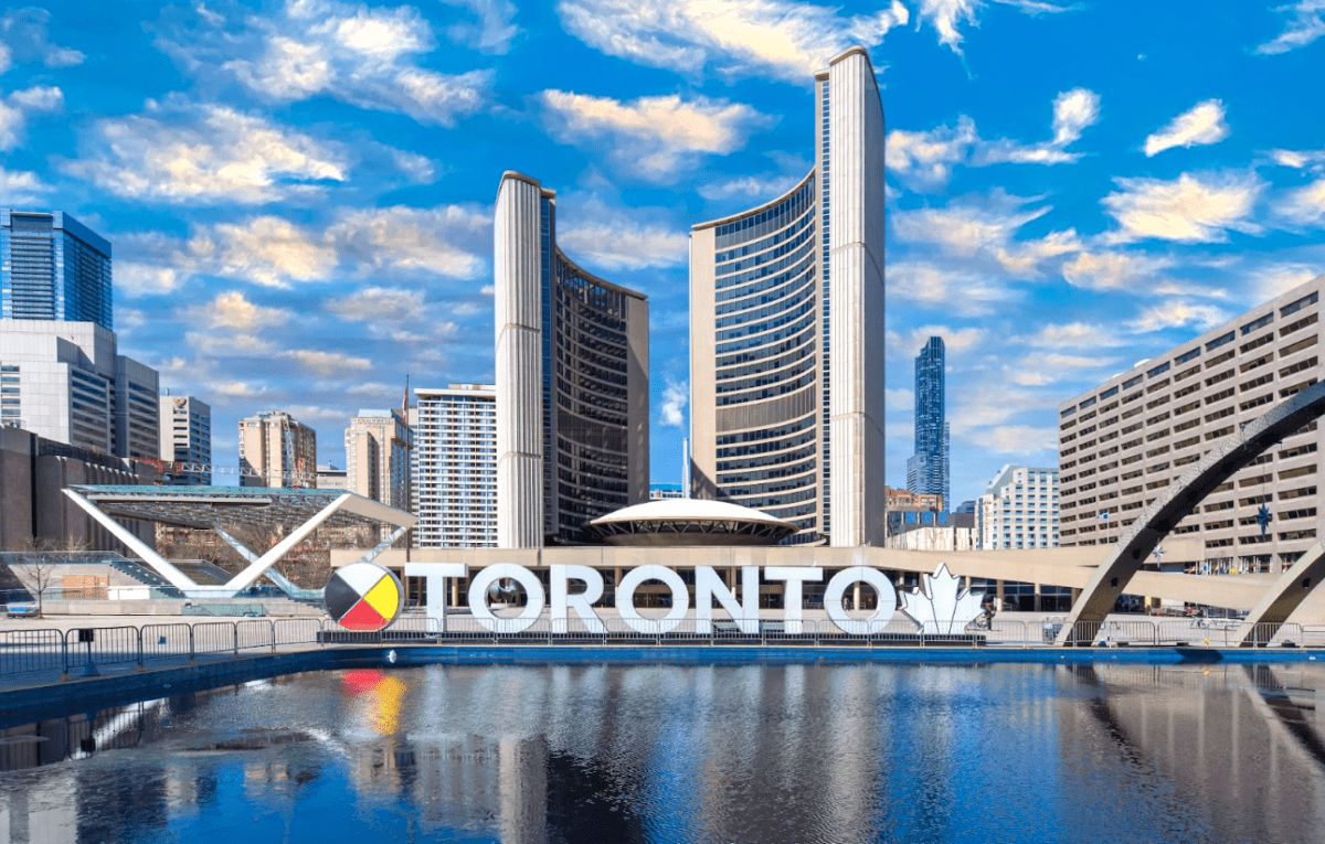 Будівля мерії Торонто (Toronto City Hall) з двома вигнутими вежами, знаменитим написом TORONTO та відображенням у басейні на площі Nathan Phillips Square.