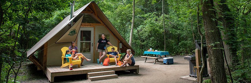 Сім'я відпочиває на терасі намету oTENTik серед лісу в таборі Camp Henry національного парку Пойнт-Пелі.
