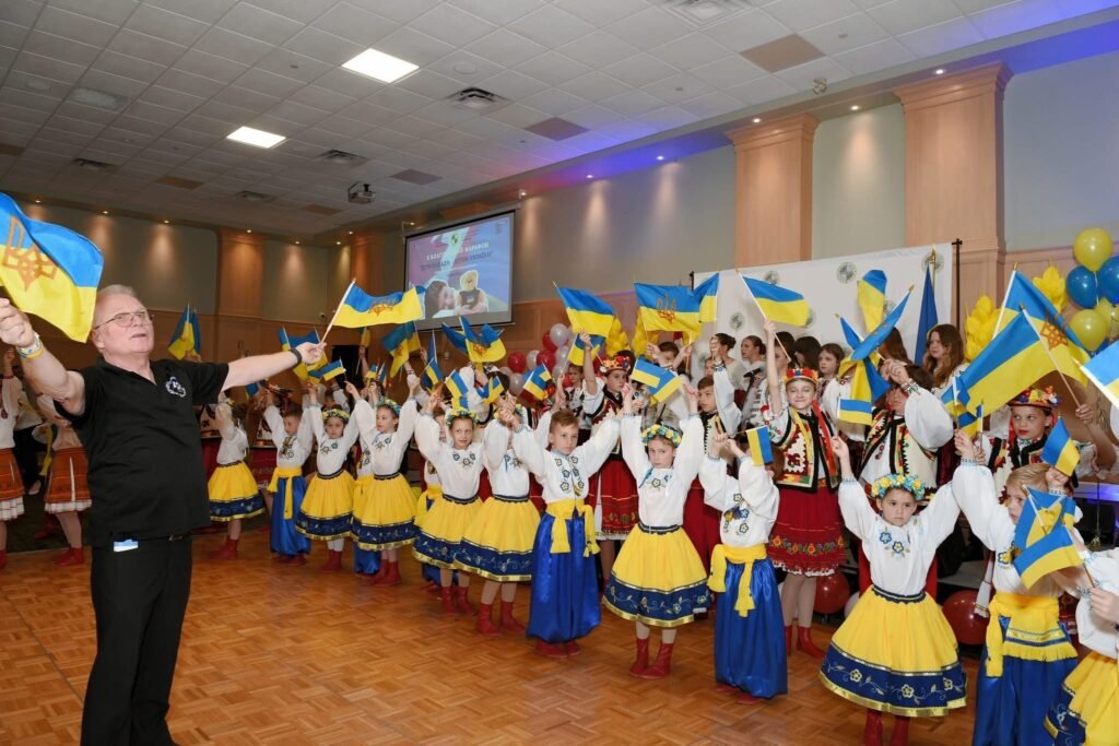 Група дітей в українському національному вбранні з прапорцями України на сцені під час благодійного заходу в Торонто.