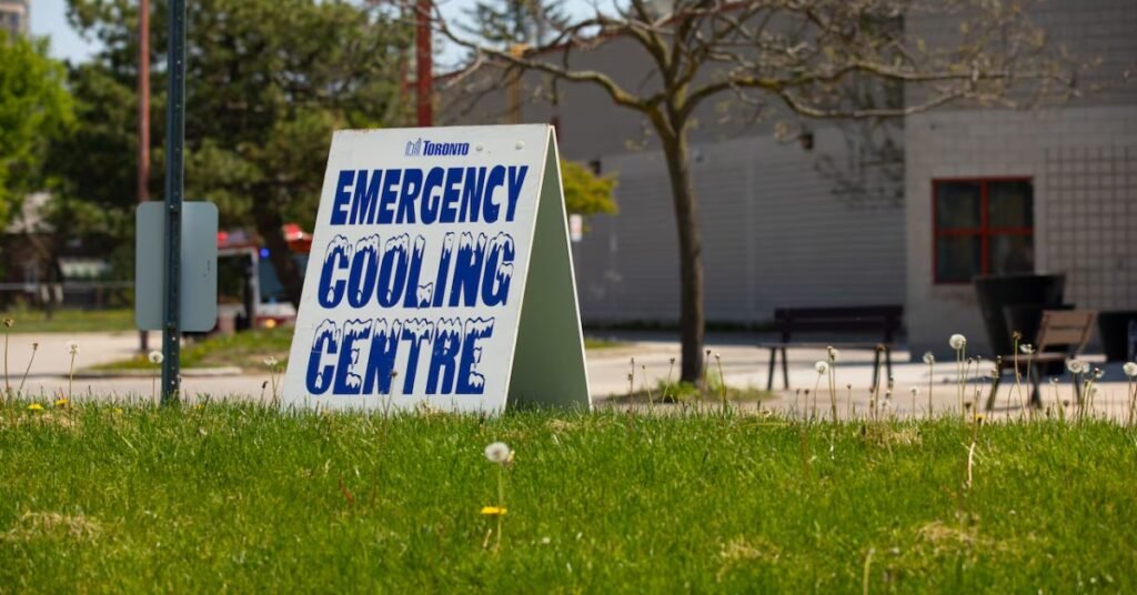 Білий інформаційний стенд-тринога з написом Emergency Cooling Centre синіми літерами на зеленому газоні в Торонто.