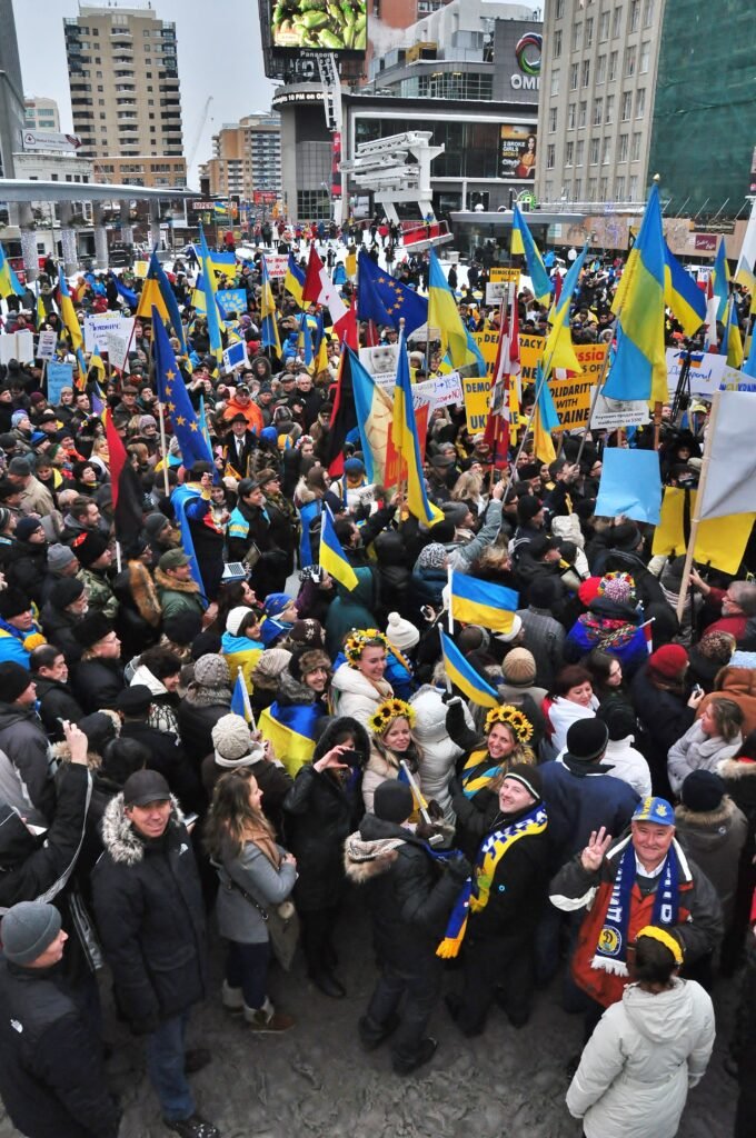 Масштабне зібрання людей з українськими та європейськими прапорами на площі Дандас у Торонто під час акції солідарності.