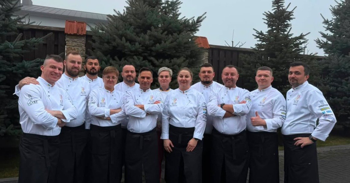 Групове фото команди українських шеф-кухарів у білих кітелях на фоні ялин